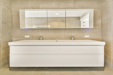A contemporary bathroom design featuring a sleek sink, stylish faucets, and a large mirror. The neutral tones and clean lines create a relaxing atmosphere.