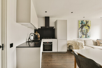 A sleek, modern kitchen featuring minimalist design with black countertops, white cabinets, and contemporary decor. Ideal for functional living spaces.