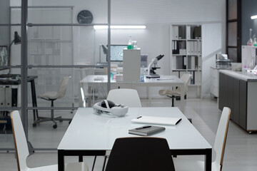 Laboratory with clean white workstations, chairs, and scientific equipment. Ready for research activities with books and devices placed on tables