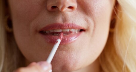 Close-up of a woman's lips during makeup application. A woman paints her lips with lip gloss