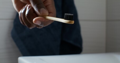 A man squeezes toothpaste onto a toothbrush. Close-up of his hands, unrecognizable person