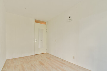 A minimalistic empty room featuring plain white walls and a wooden floor. A door with a glass panel adds a touch of simplicity to the space.