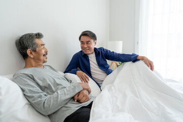 Fototapeta premium Asian elderly male gay couple sitting on bed and talk to each other. 
