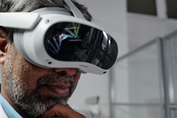 African American man engaged in virtual reality technology experience, holding headset close to his eyes, in bright indoor environment