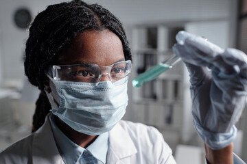Scientist wearing protective gear is carefully holding pipette in laboratory, performing experiment...