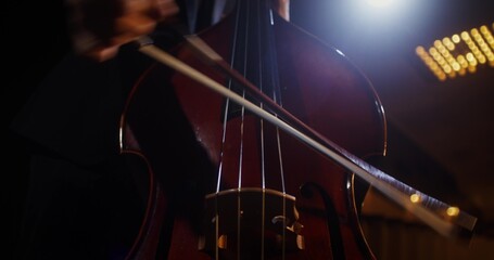 Fototapeta premium A man plays the double bass using a bow. Solo performance on the theater stage
