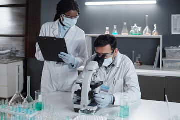 Scientists conducting research in modern laboratory with various glassware and equipment. One...