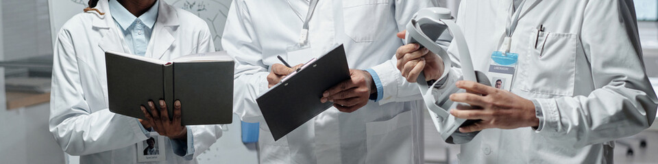 Group of medical professionals wearing lab coats, holding and using medical devices for discussing...