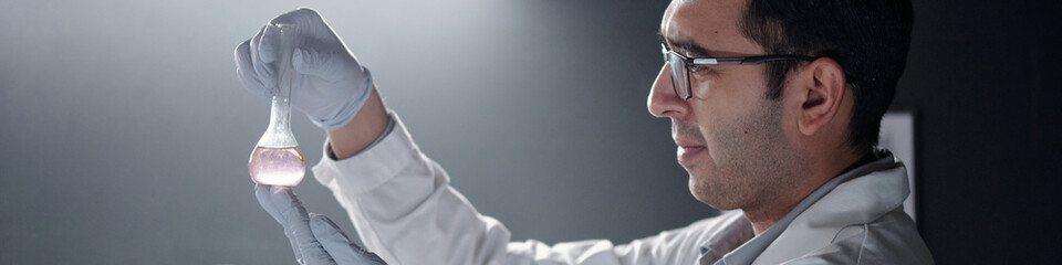 Fototapeta premium Scientist carefully analyzing chemical sample in laboratory environment wearing safety gloves and eyewear. Light background highlights his concentration and precision