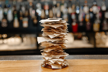 pile of spiked papers, restaurant and bar checks with orders on bar counter, alcohol bottles in...