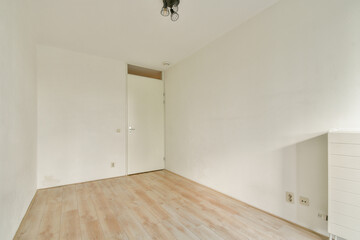 An empty minimalist room featuring light-colored walls and a wooden floor. This setting provides a serene and spacious atmosphere ideal for various uses.