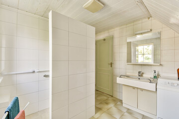 A bright and clean modern bathroom featuring tiled walls, a sink, and a shower area, illuminated by natural light from a window.