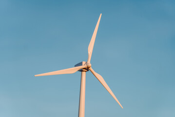 toy white wind turbine outdoors at sunset in summer, blue sky in background, alternative...
