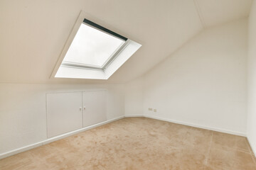 A bright, minimalist room featuring a skylight and soft beige carpeting. The walls are crisp white, creating a serene and airy atmosphere.