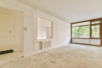 Obraz premium An empty, minimalist room featuring large windows that allow abundant natural light to flood in. The unfinished floor adds a sense of openness and potential.