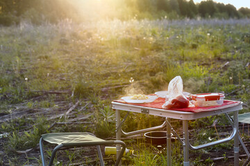 Disposable plates with hot pasta and tomatoes on a tourist table. Late tourist dinner in the open air.