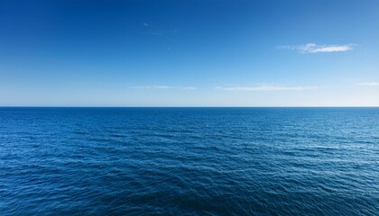 Obraz premium A calm blue ocean under a clear sky stretches to the horizon, creating a serene and tranquil seascape.