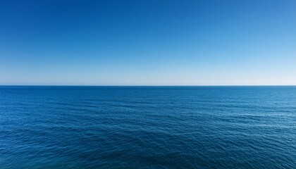 Fototapeta premium Clear blue sky meets calm ocean waters at the horizon, creating a serene and tranquil seascape.