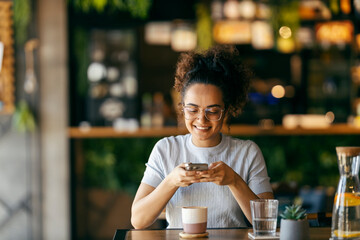 Young influencer sitting in coffee shop and taking pictures of her coffee with mobile phone.