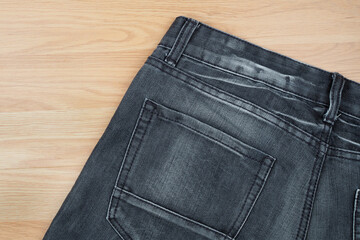 Black jeans on wooden background. closeup