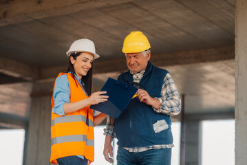 Construction workers discussing blueprint on building site