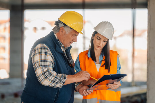 Construction workers discussing blueprint on building site