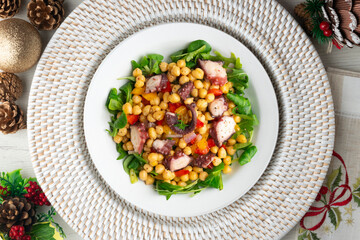 Salpicon de pulpo. Octopus salad with chickpeas, arugula and vegetables. Top view table with christmas decorations.