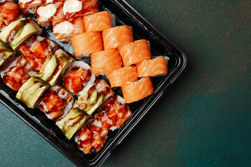 Sushi platter with various rolls and slices arranged on a black tray