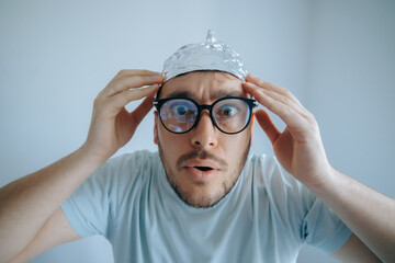 Man wearing an aluminum foil hat expresses disbelief and paranoia while concerned about conspiracy...