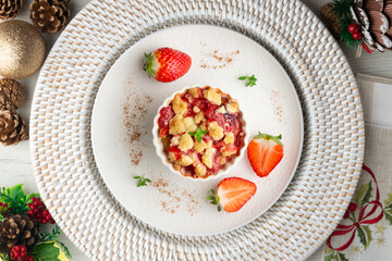 Individual baked strawberry crumble. Top view table with christmas decorations.