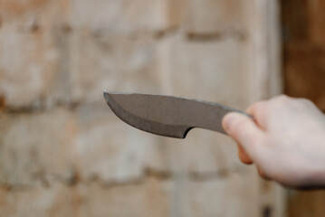 hand with metal knife, wooden block stand as target in background, throwing knives, sports competition, selective focus