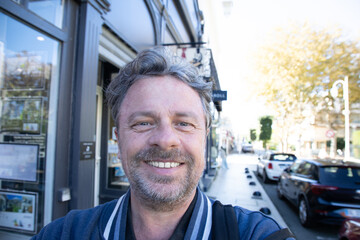 handsome happy man middle aged smiling outside tour tourist in selphie smartphone picture portrait by smart telephone