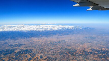 Aerial view of snow-capped mountains and vast landscape from airplane window