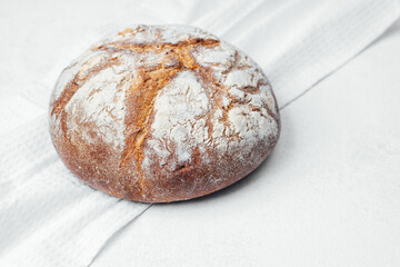 Freshly baked round bread resting on a white cloth background