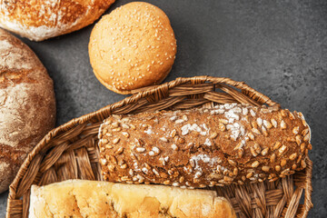 Freshly baked bread assortment displayed in a rustic basket on a dark surface