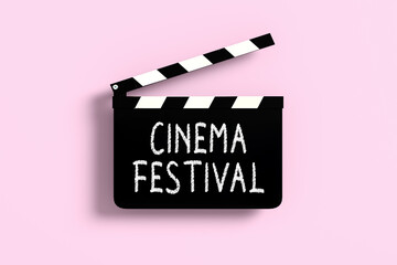 Naklejka premium Cinema festival written on a clapperboard on pink background