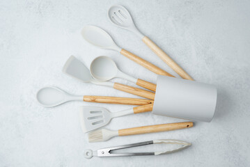 Modern kitchen utensils arranged in a decorative holder on a light surface
