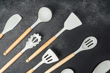Kitchen utensils arranged on a dark countertop with wooden handles