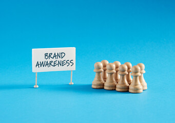 Chess pawns standing next to banner with the message Brand Awareness.