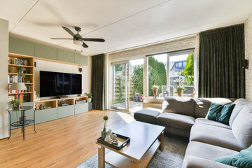 A stylish modern living room featuring a cozy sofa, sleek furniture, and large sliding glass doors that open to a lush garden view.