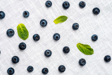 Fresh blueberries and mint leaves arranged on a white linen tablecloth