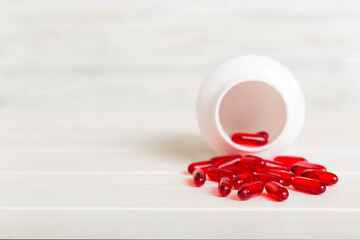 Red pills spilled around a pill bottle. Medicines and prescription pills flat lay background. Red...