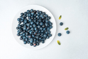 Fresh blueberries arranged on a plate with a few scattered pieces nearby