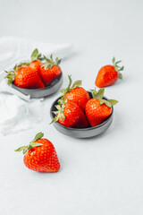 Fresh strawberries arranged in bowls on a light surface in a kitchen setting