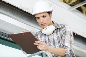 female builder writing on clipboard