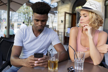 young couple looking smartphone in bar terrace