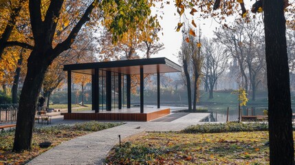 Modern pavilion nestled within an autumnal park landscape.