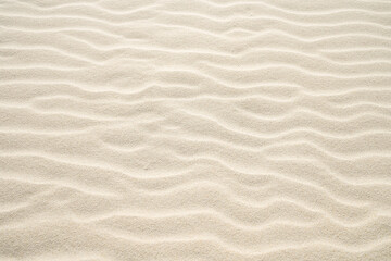 Light beige sand with wavy drifts. Natural surface as a background.
