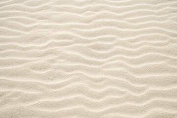 Light beige sand with wavy drifts. Natural surface as a background.
