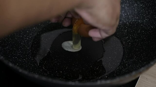 Cooking fried eggs sunny side up with a sizzling oil in frying pan.
